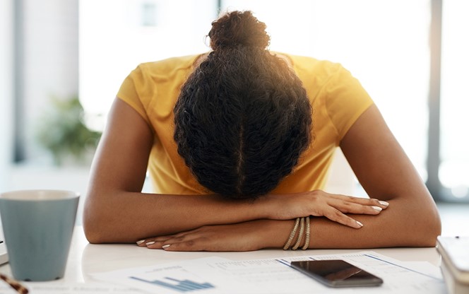 Young Businesswoman With Her Head Down On Her Desk