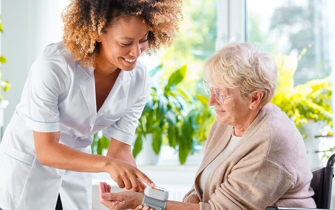 Home Carer Checking Blood Pressure Of Elderly Lady