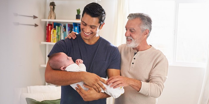 Proud Senior Hispanic Man Standing With His Adult Son Holding His Four Month Old Boy