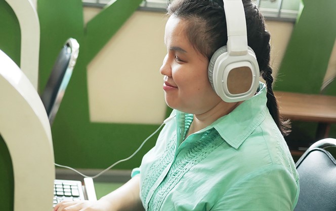 Woman In Headphone Typing On Computer Keyboard