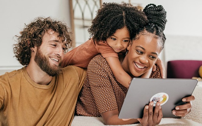 Smiling Parents And Daughter At Home Watching Online Movie Together