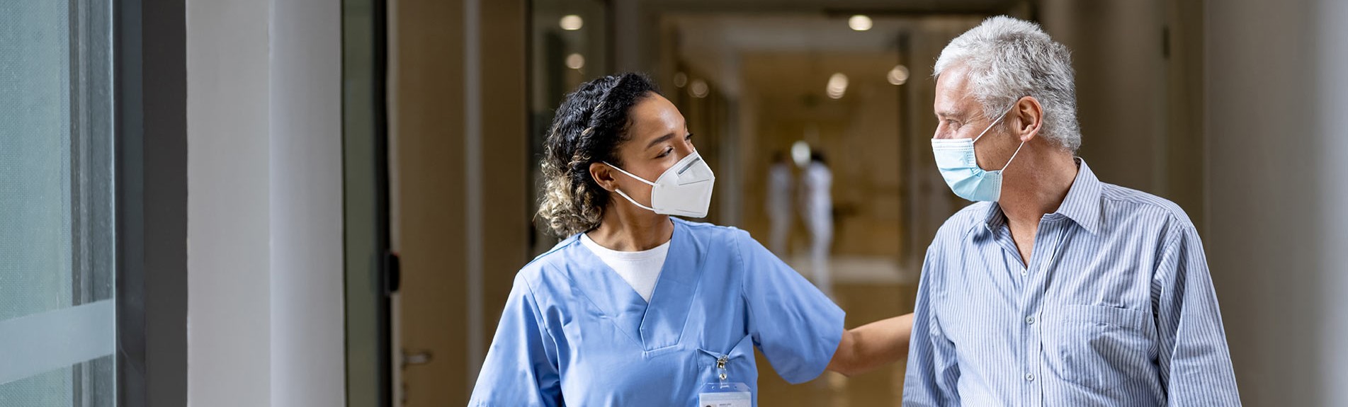 Doctor Talking To A Patient In The Corridor Of A Hospital While Wearing Face Masks
