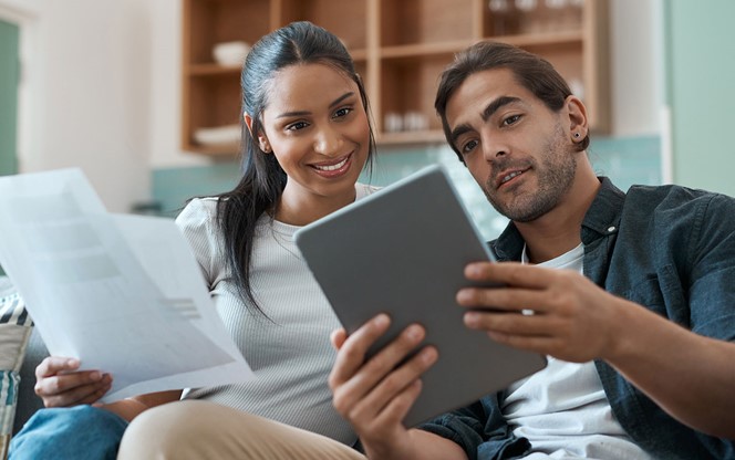 Young Couple Doing Paperwork While Using A Digital Tablet At Home