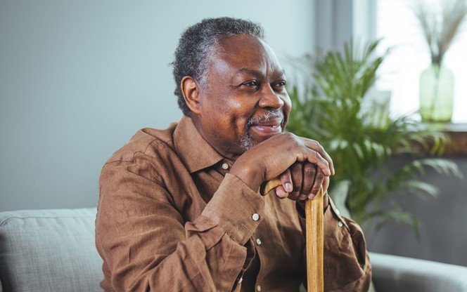 Thoughtful Elderly Man Sitting Alone At Home With His Walking Cane