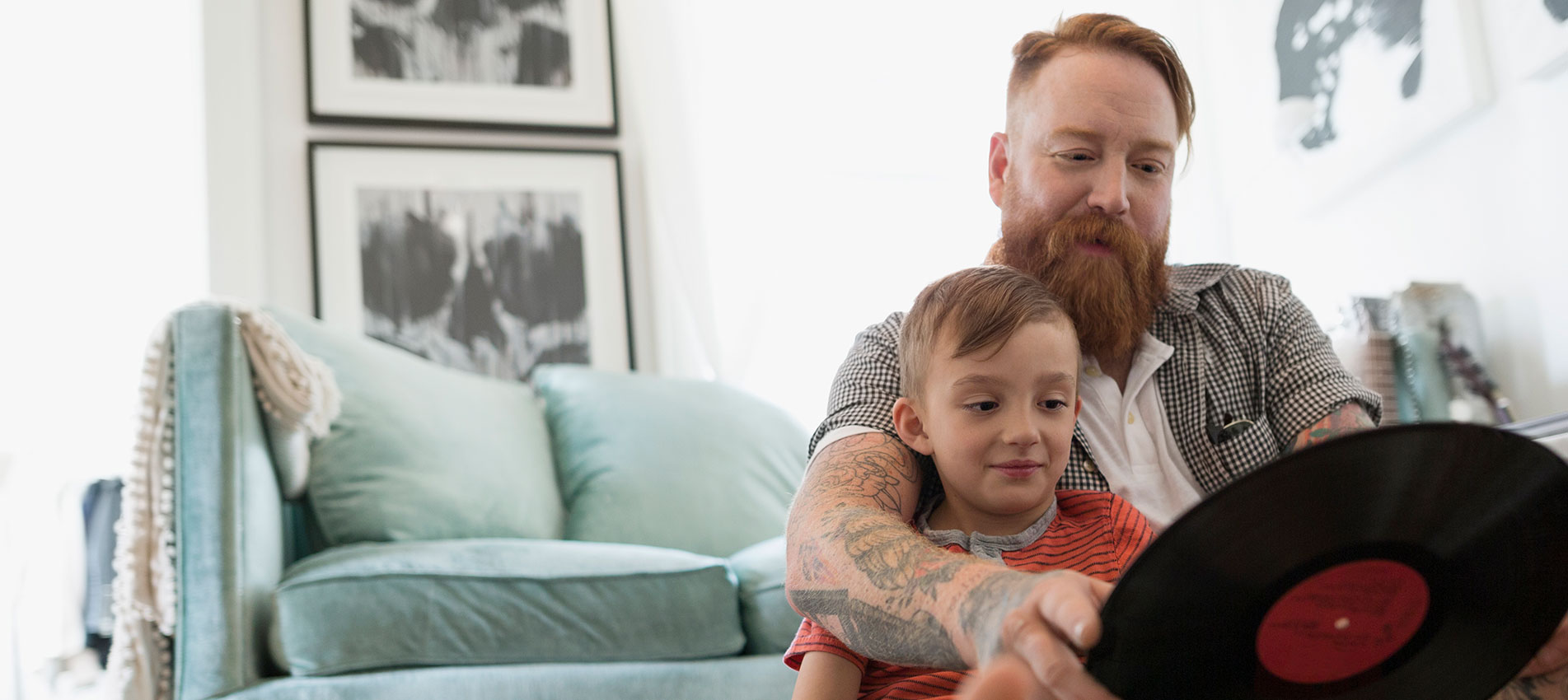 Father And Son Looking At Records On Living Room Floor