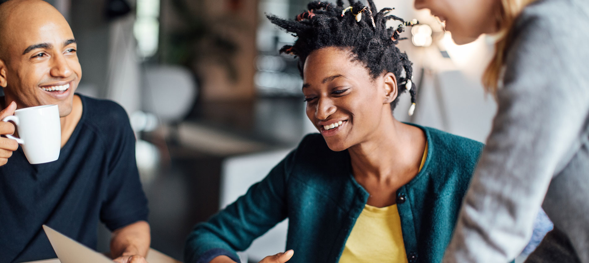 Happy Business Colleagues Talking While Using Laptop At Office