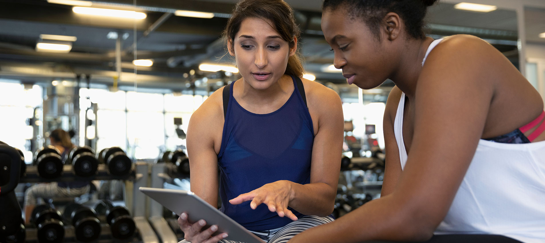 Personal Trainer With Digital Tablet Talking With Woman In Gym