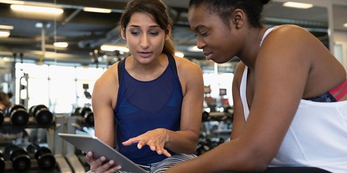 Personal Trainer With Digital Tablet Talking With Woman In Gym
