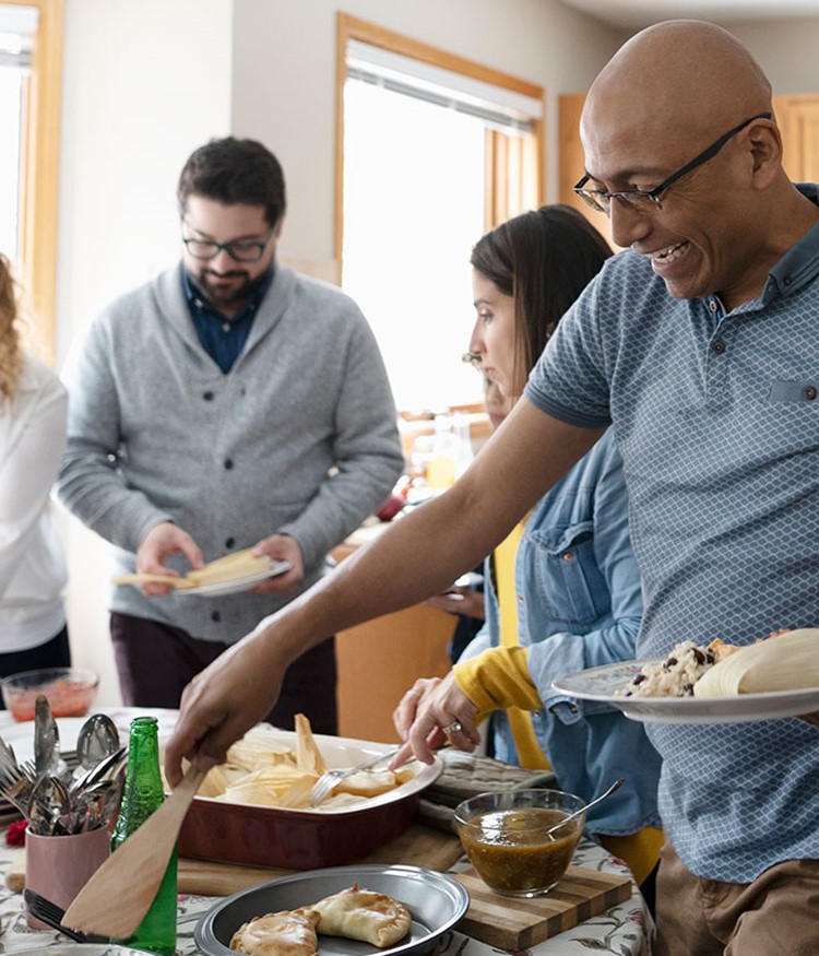 Latinx Family Enjoying Buffet Dinner In Kitchen