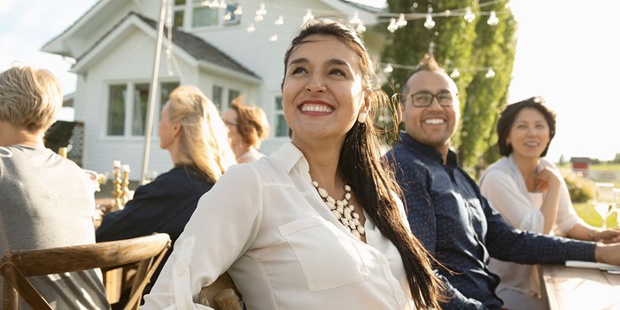 Smiling Woman Enjoying Garden Party At Sunny Patio Table