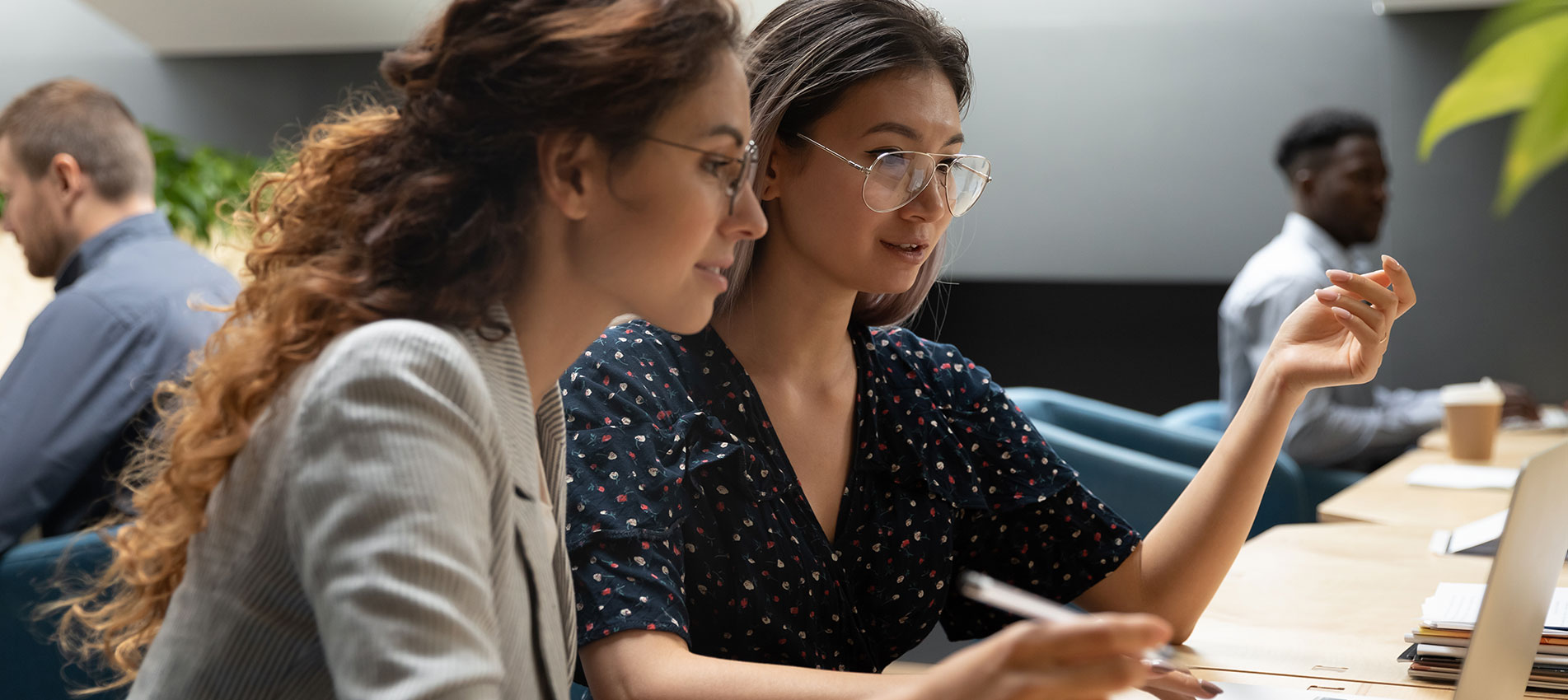 Female Mentor Teaching Caucasian Intern Explaining Online Project