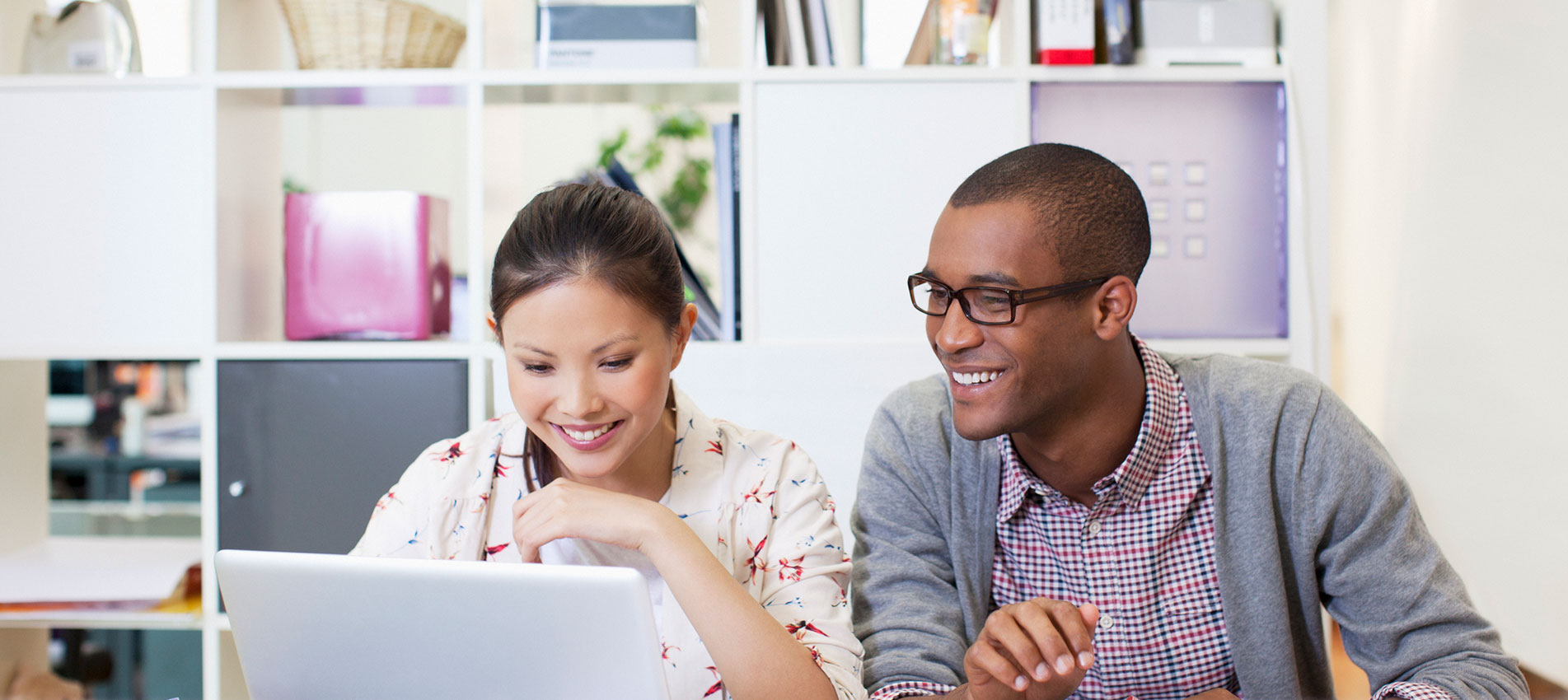 Businessman and businesswoman using laptop in office