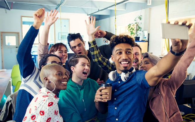 Enthusiastic creative business team taking selfie in office