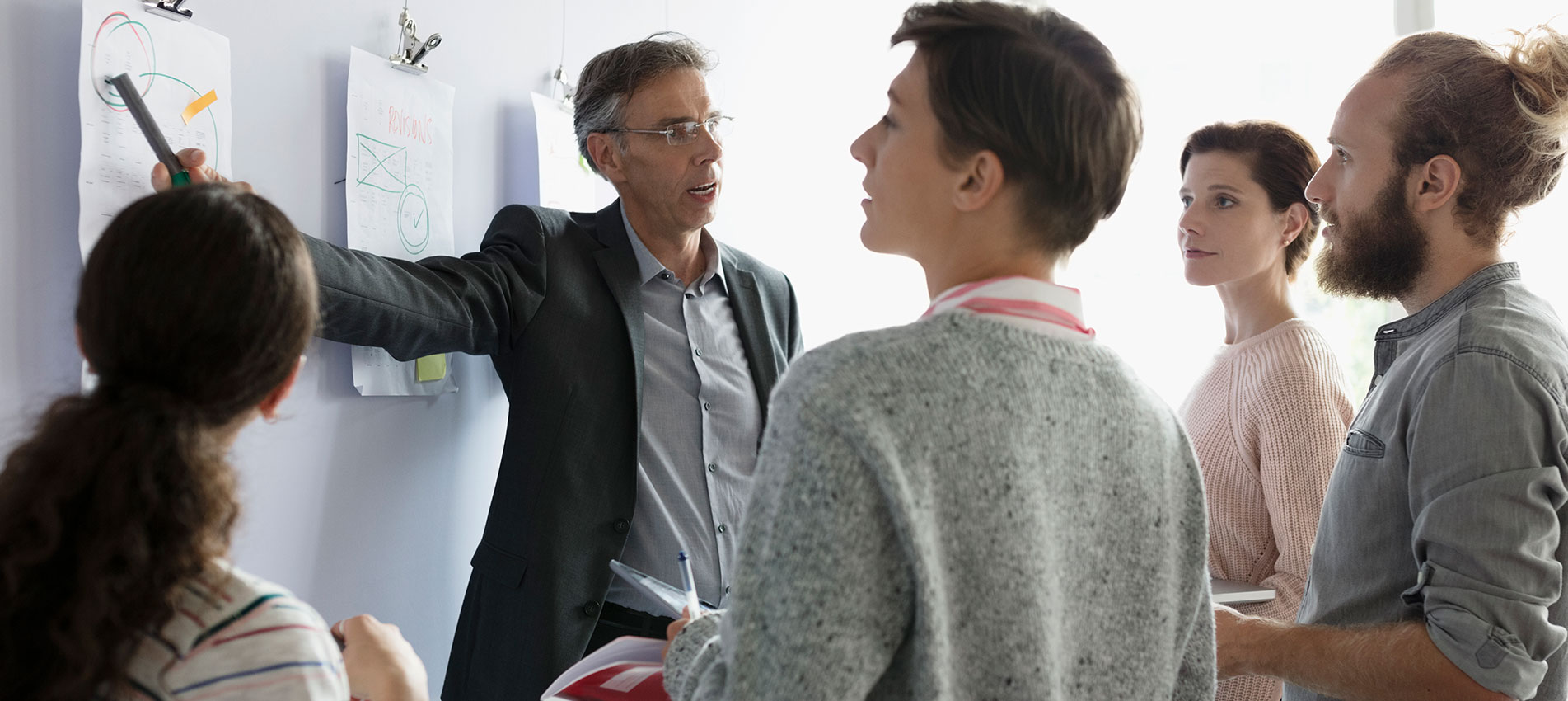 Professor And Mature Students Discussing Diagrams In Classroom