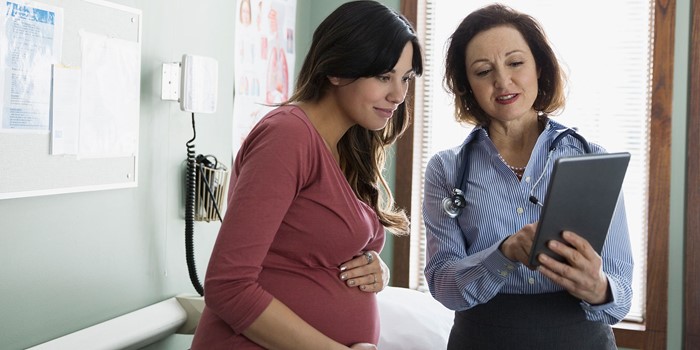 Doctor And Pregnant Woman Looking At Digital Tablet
