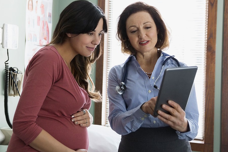 Doctor And Pregnant Woman Looking At Digital Tablet