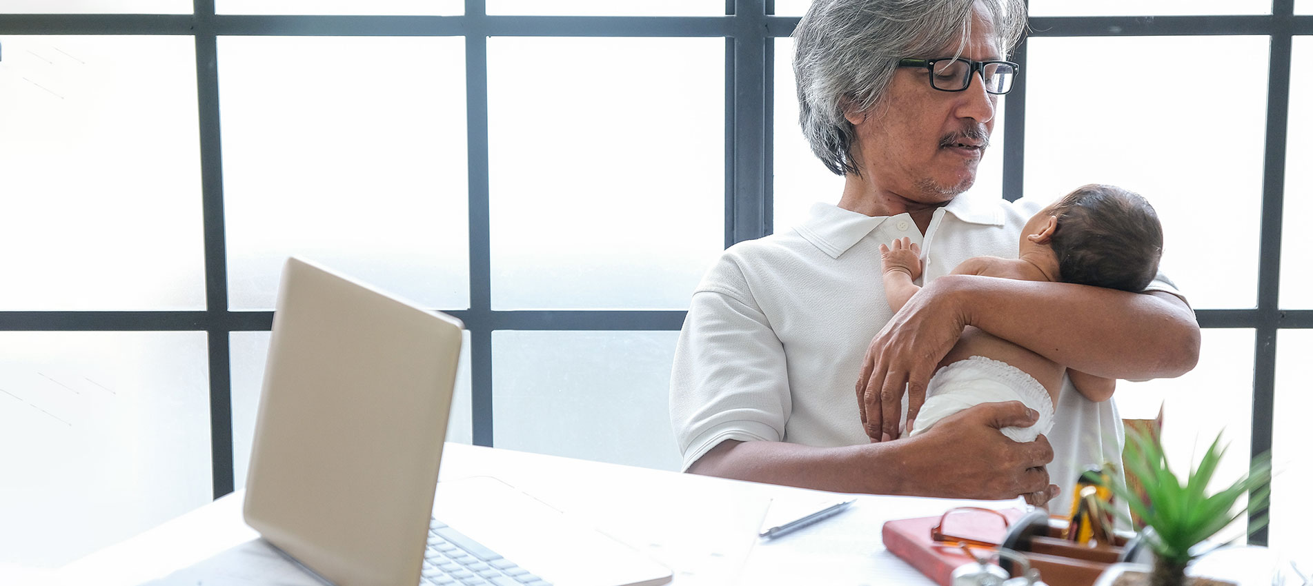 Grandpa Using Laptop While Grandson Reading Newspaper