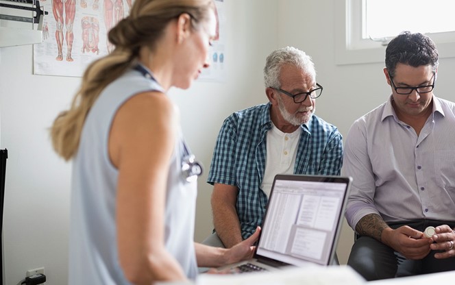 Female Doctor With Laptop Senior Male Patient And Son Prescription