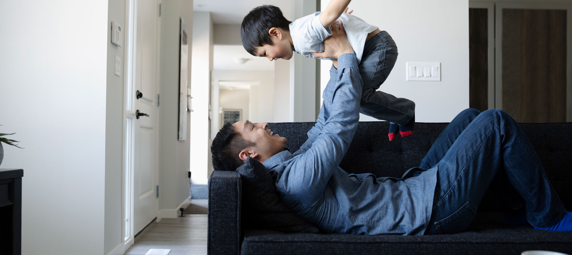 Playful Father And Son On Living Room Sofa