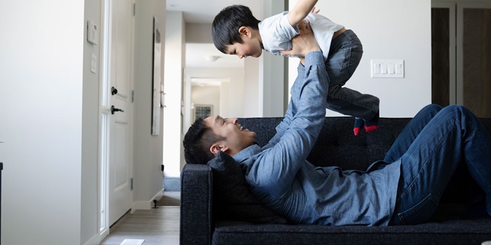Playful Father And Son On Living Room Sofa