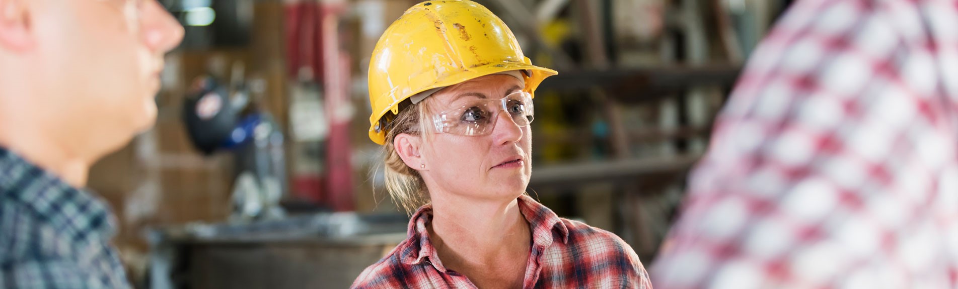 Woman Working In Factory With Group Of Men