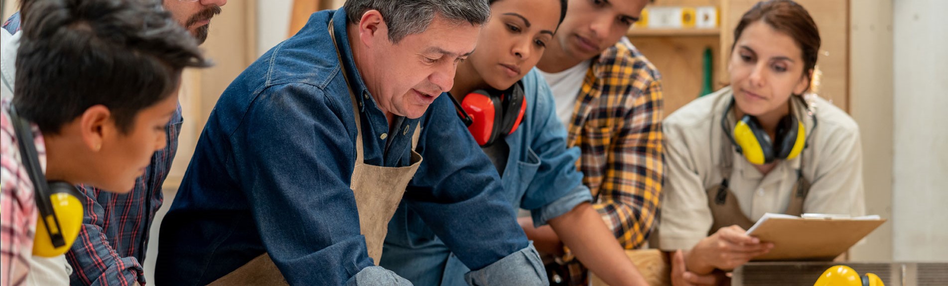 Group Of Workers At A Furniture Factory Looking At A Blueprint