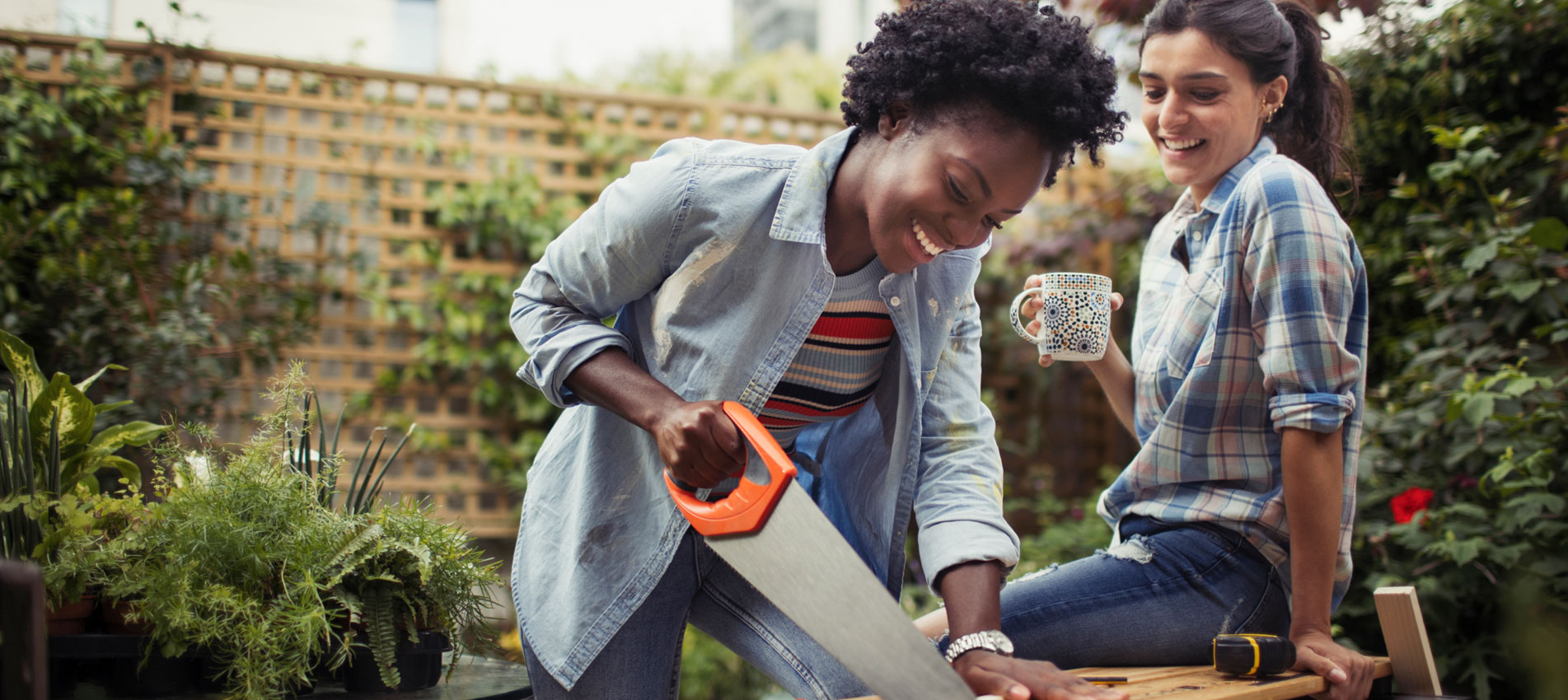 Women Drinking Coffee And Cutting Wood With Saw On Patio