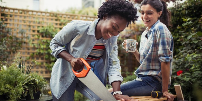 Women Drinking Coffee And Cutting Wood With Saw On Patio