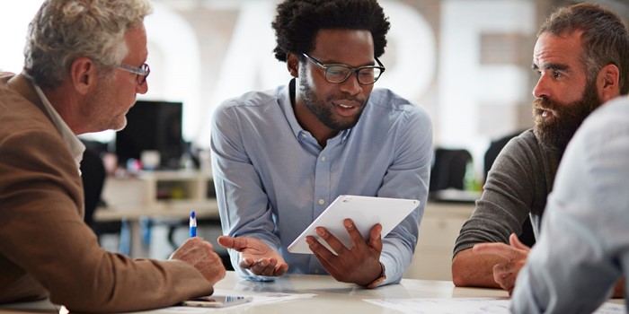 Businessman Presenting To Co Workers With Tablet