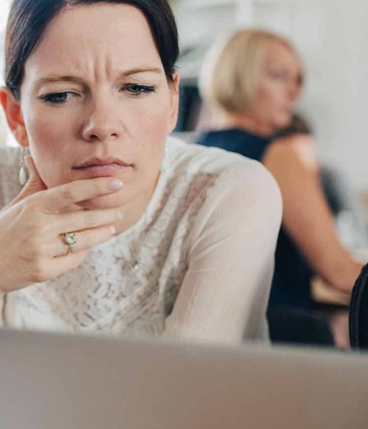 Confused Businesswoman Looking At Laptop While Sitting At Desk
