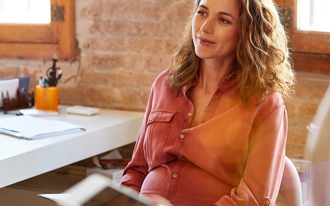 Pregnant Businesswoman Looking Away At Desk
