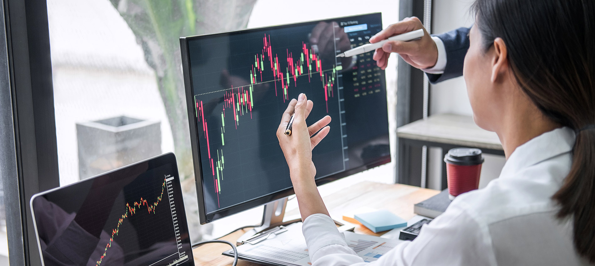 Businesswoman With Colleague Discussing Graph On Desktop