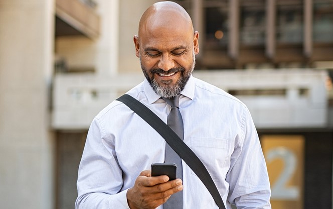 Satisfied Businessman Walking While Using Phone