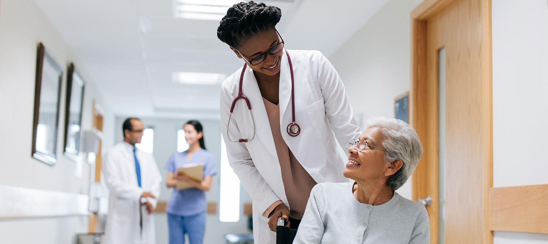 Female Doctor Pushing Senior Woman On Wheelchair
