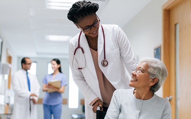 Female Doctor Pushing Senior Woman On Wheelchair