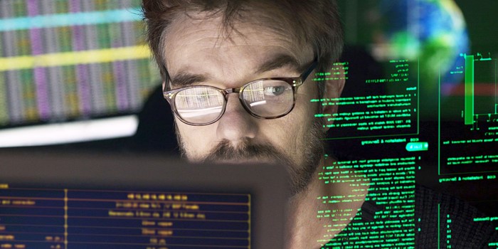 Stock close-up photo of a mature man surrounded by monitors & a holographic display which he is reading