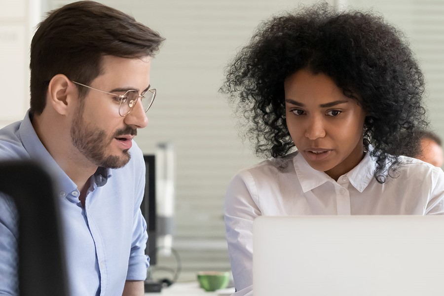 Serious African Leader Explaining Online Project On Laptop To Coworkers