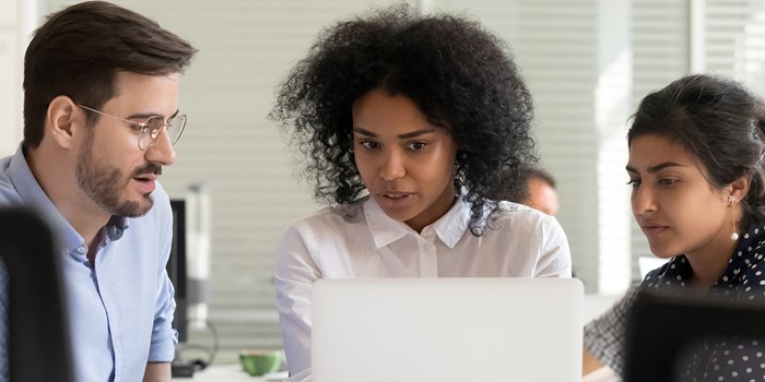 Serious African Leader Explaining Online Project On Laptop To Coworkers