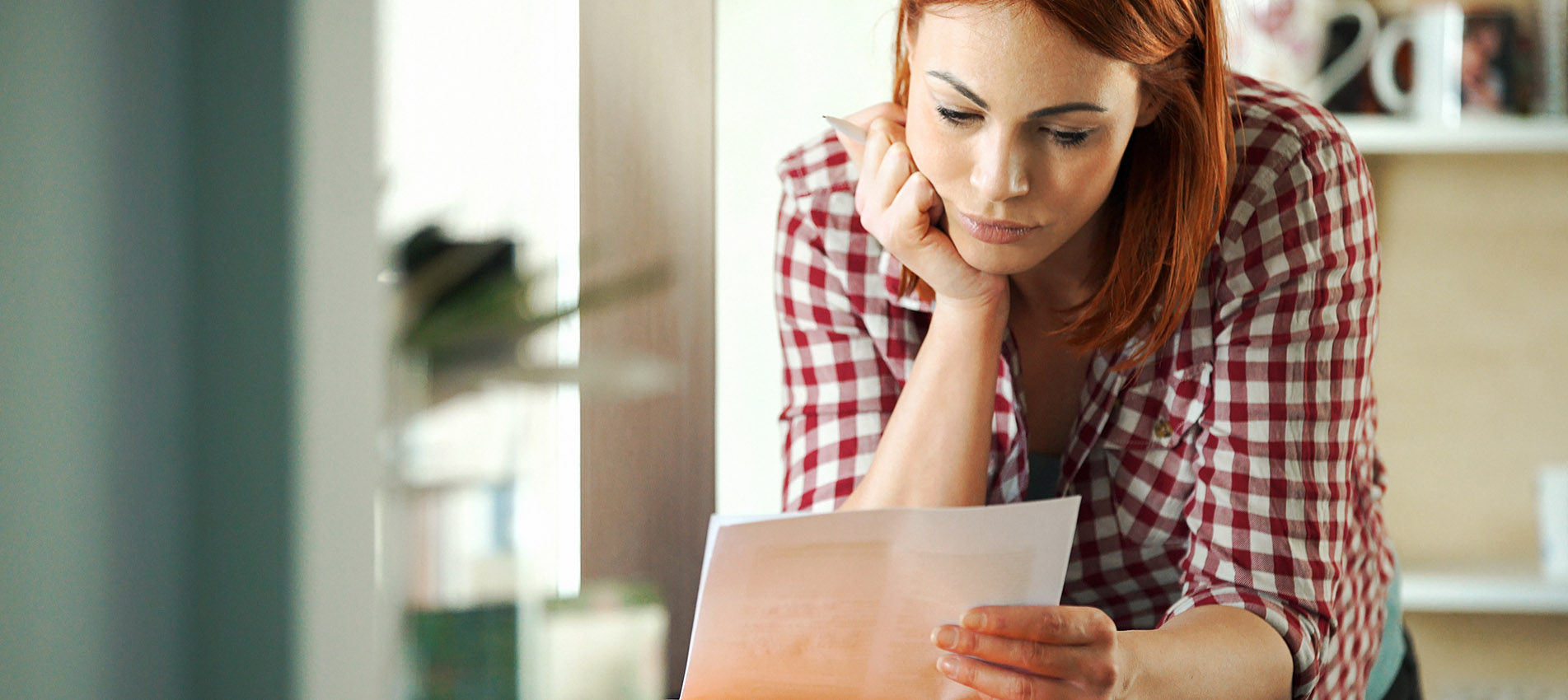 Closeup of attractive mid 30's housewife looking at monthly bills that seem to have skyrocketed