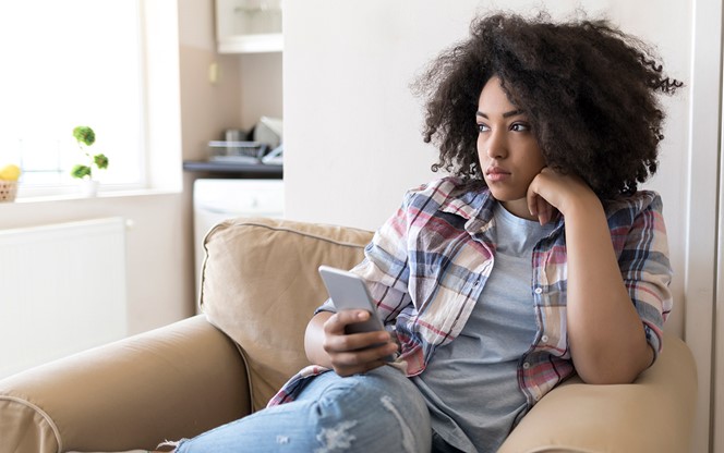 Pensive Young Woman Sitting At Home And Using Smart Phone