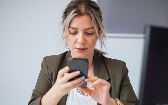 Young Businesswoman Using Mobile Phone At Work