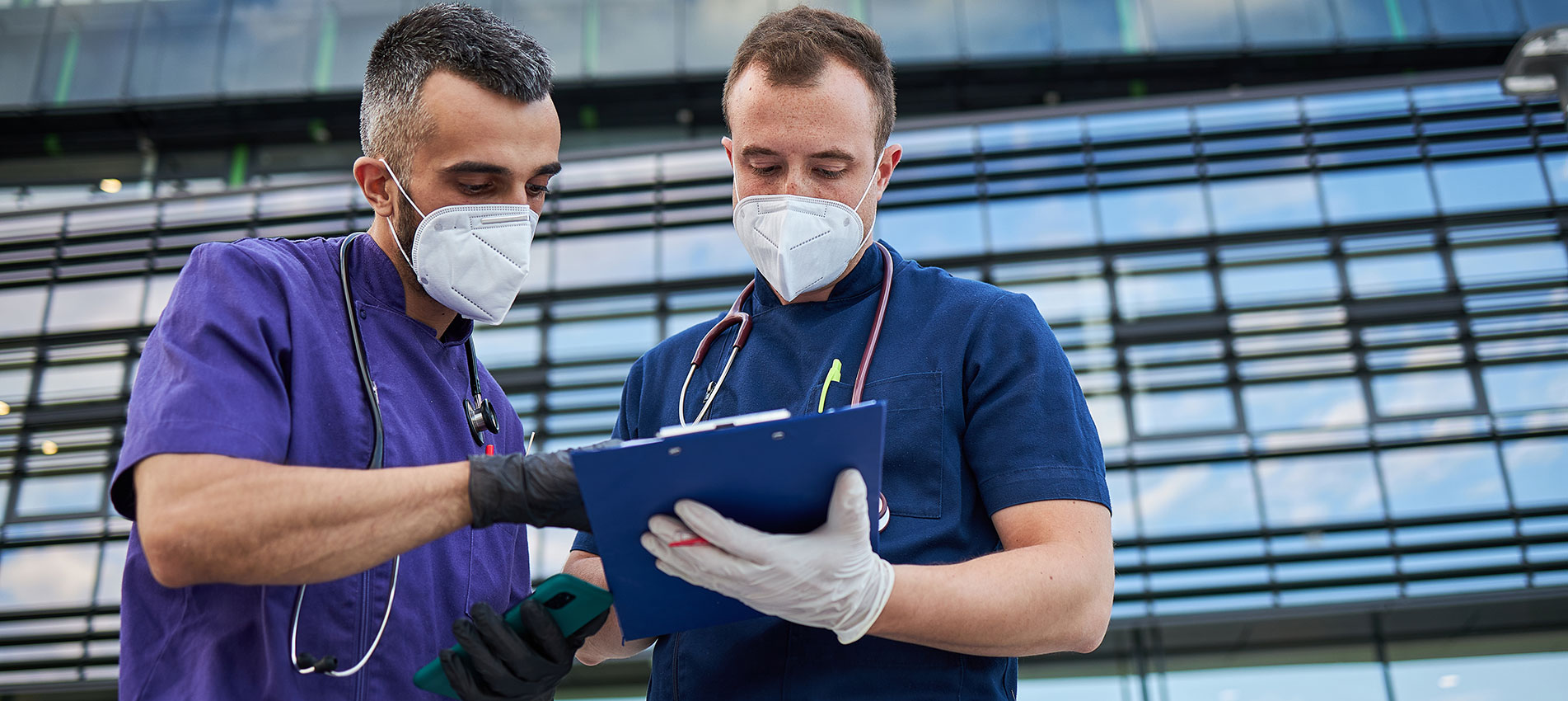 Medical Colleagues Working With A Note Pad And Statistics In Front Of A Hospital