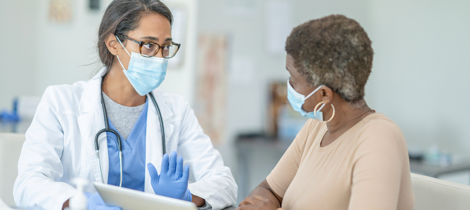 Female Doctor And Patient In Personal Protective Equipment At Medical Exam