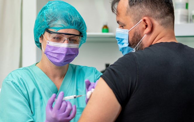 Mid Adult Man Getting A Vaccine Shot Nurse In Protective Workwear Injecting It With Syringe