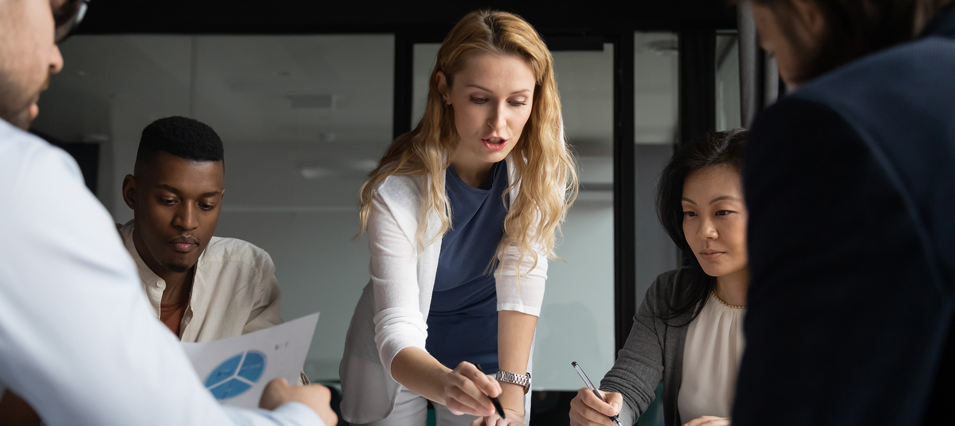 Young Businesswoman Explaining Research Results In Graphs To Colleagues