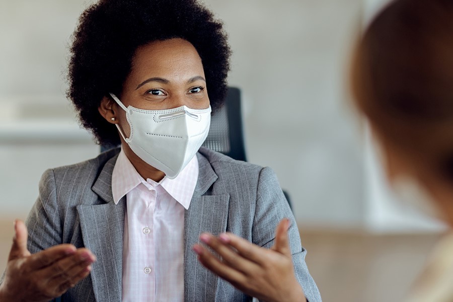 Black Female Financial Consultant Talking To Her Client And Wearing Protective Face Mask During The Meeting