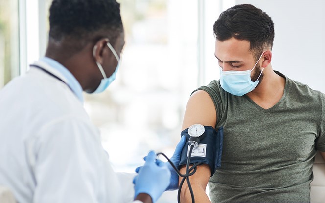 A Male Doctor Examining A Young Man With A Blood Pressure Gauge
