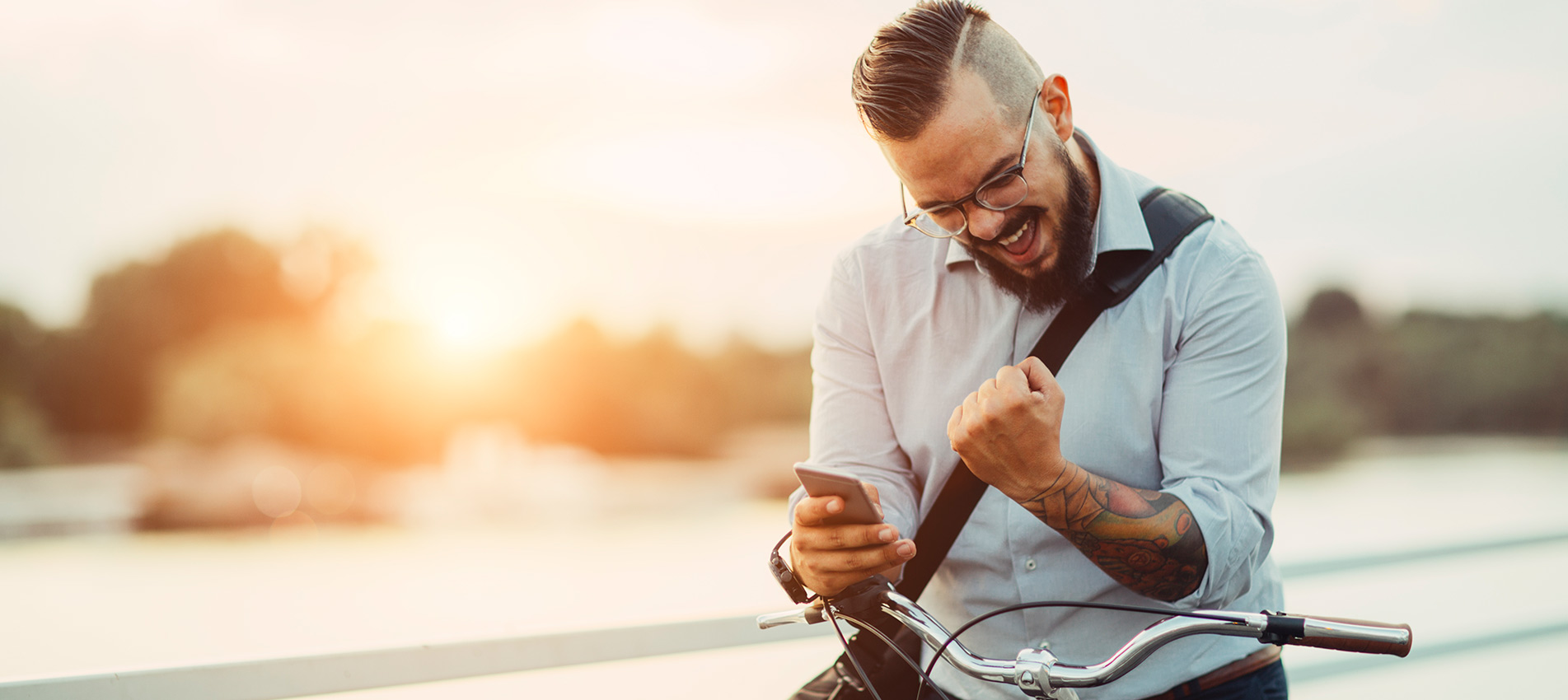 Young Happy Businessman Pushing His City Bicycle And Using His Smart Phone