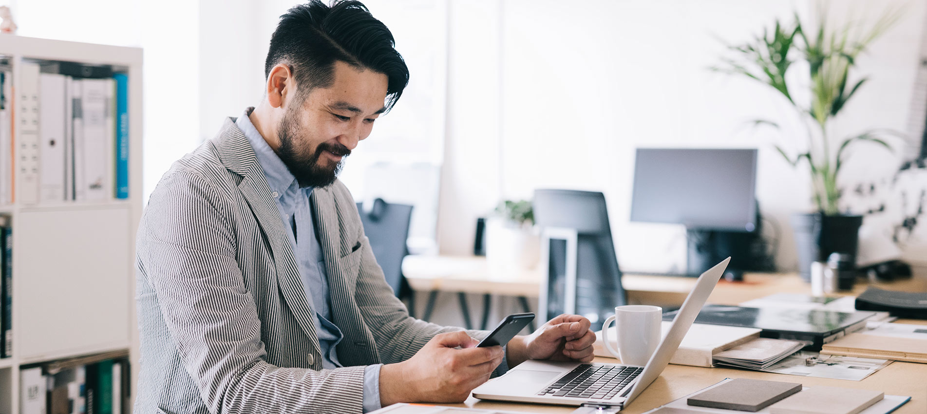 Positive Asian Small Business Owner Checking His Smartphone At Work