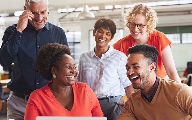 Laughing Team Of Diverse Businesspeople Working Together On A Laptop